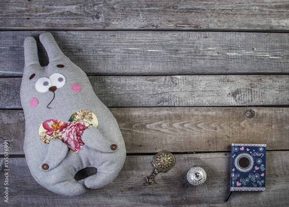 wooden background with soft toy bunny and pink heats and candle