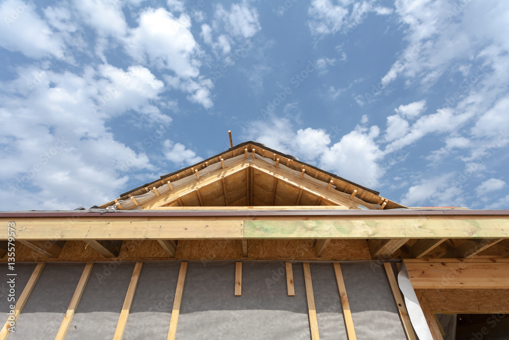 New frame house under construction. Roof with asphalt shingles, chimney and insulation material in attic New frame house under construction. Roof with asphalt shingles, chimney and insulation material in attic