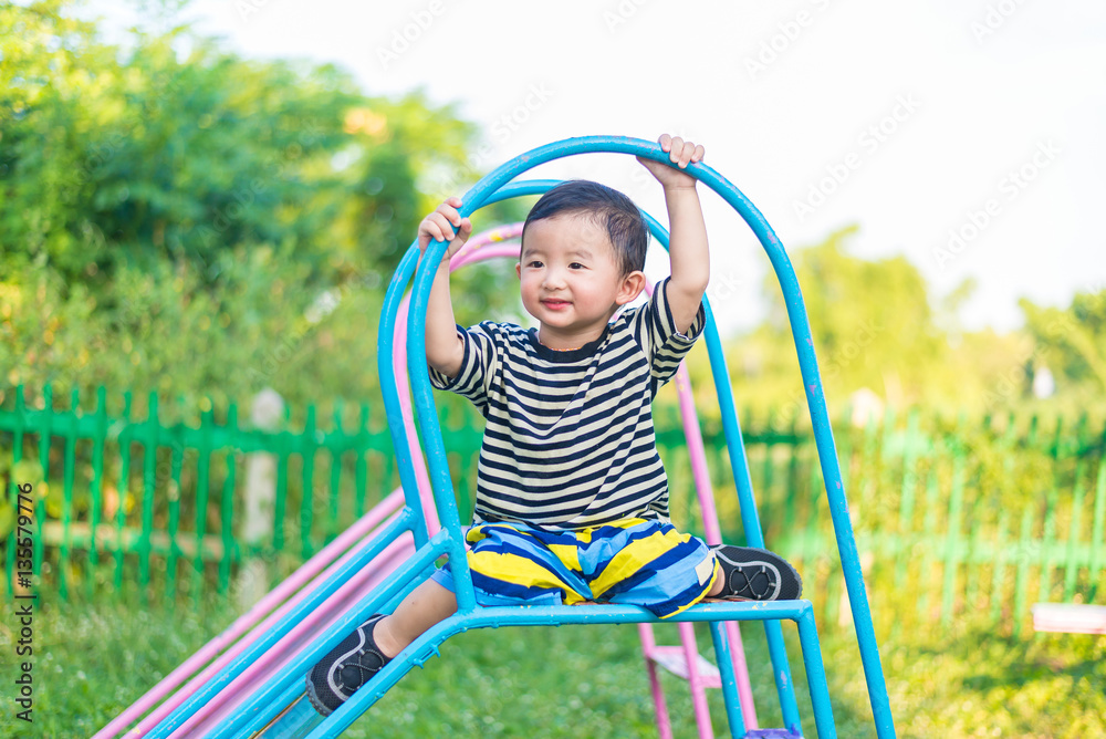 Little Asian kid playing slide at the playground Little Asian kid playing slide at the playground