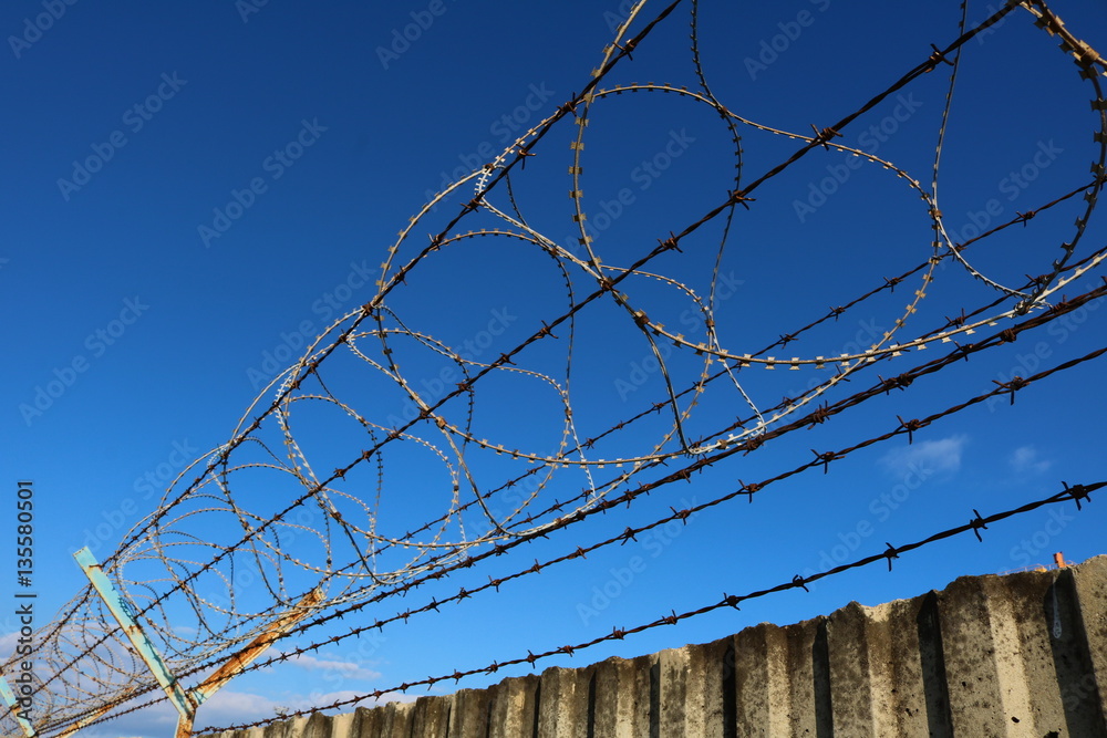 Concrete wall with barbed wire on top Concrete wall with barbed wire on top