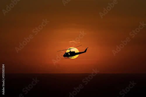 Flying helicopter silhouettes on sunset background 
The patrol helicopter flying in the twilight sky.
