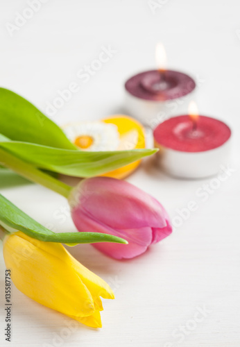 Lit candles and yellow pink tulips