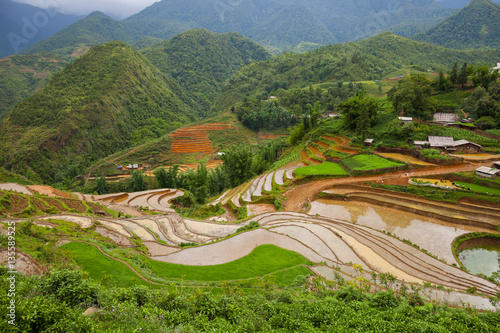 Green field terrace on mountain with village on ground in raining season located at SAPA Vietnam  photo