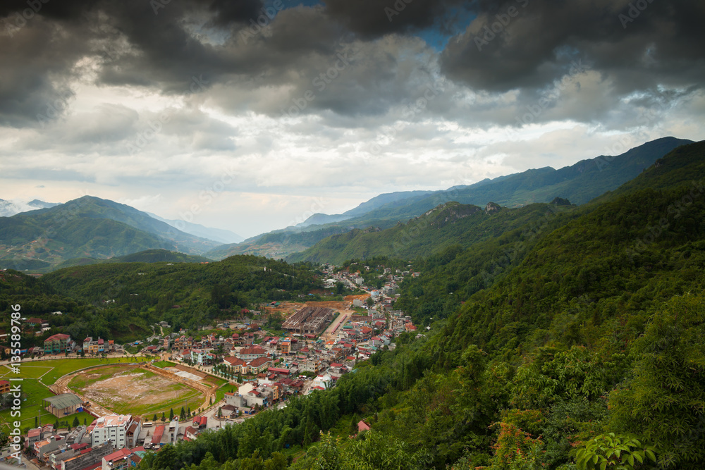 Green rice terrace on mountain view and village at ground under cloudy sky located at SAPA Vietnam 