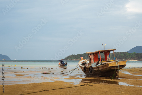 Thai old fishing small boat at low tide in the shallows.