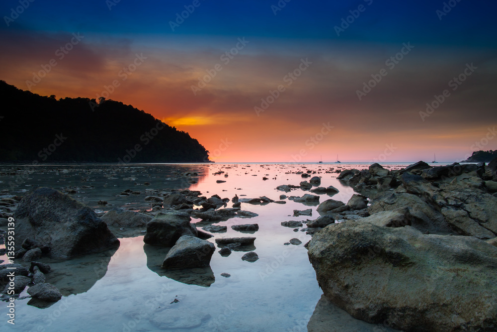 Sunset with colorful sky reflection on water and rock 