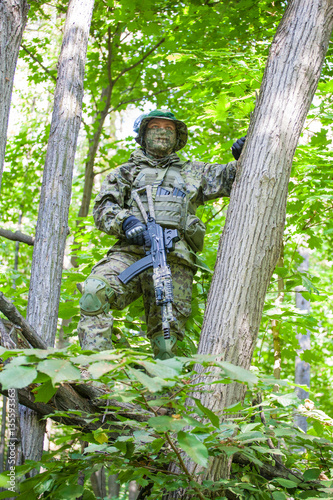 Military man in camouflage uniforms and flak jacket with a gun in the woods