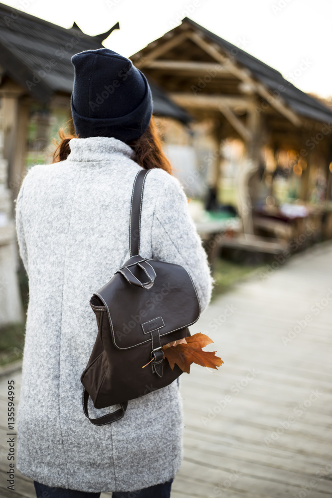 red-haired girl in a gray coat and a blue hat with yellow autumn leaves. atmosphere. authentic