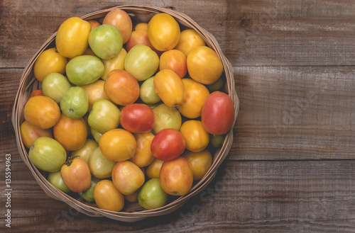 Tomatoes in a natural basket on a rushtic wooden background