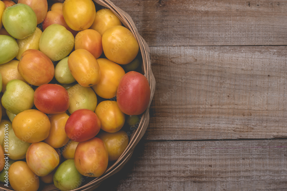 Tomatoes in a natural basket on a rushtic wooden background