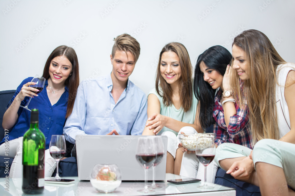 Group of five friends with laptop social networking at home.