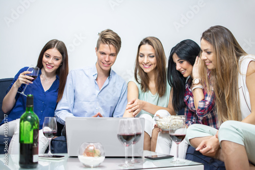 Group of five friends with laptop social networking at home.