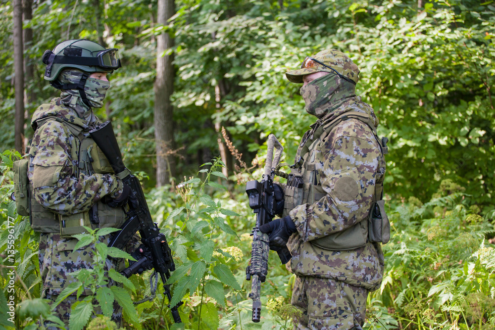 Military man in camouflage with guns in the woods