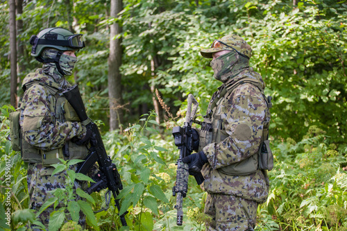 Military man in camouflage with guns in the woods