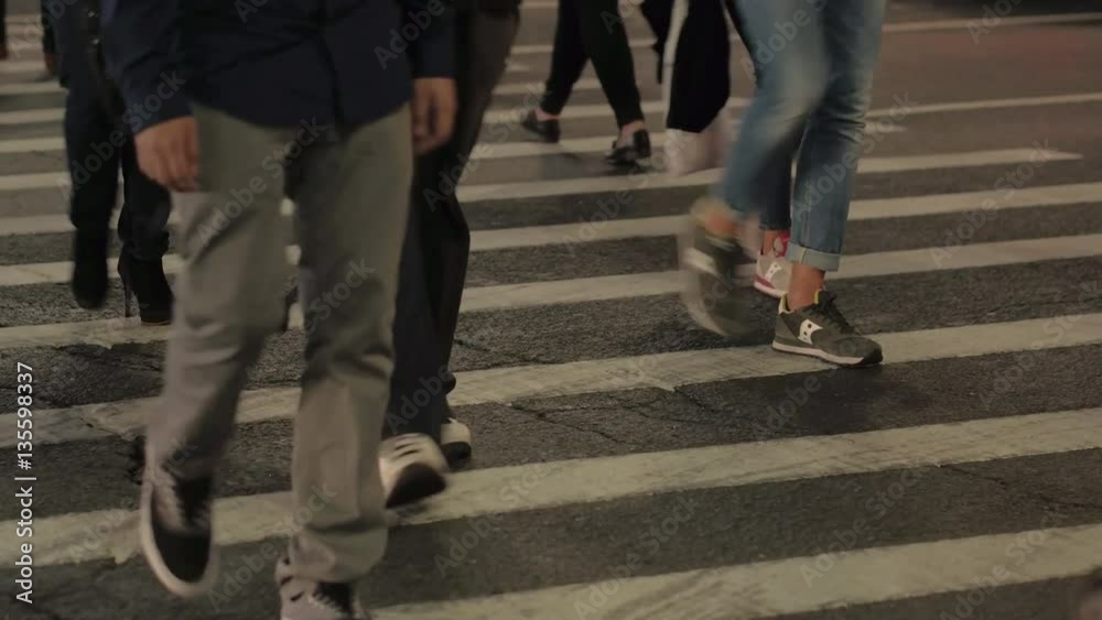 DOF: Detail of human legs walking on crowded pedestrian crossing in the evening DOF: Detail of human legs walking on crowded pedestrian crossing in the evening