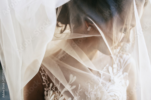 Light veil hides tender young bride Fototapeta