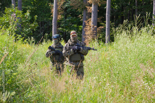 Military man in camouflage with guns in the woods