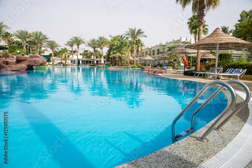 Large swimming pool with palm trees © badahos