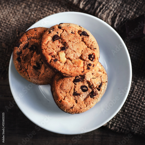 Chocolate chip cookies on white plate dark old wooden table with