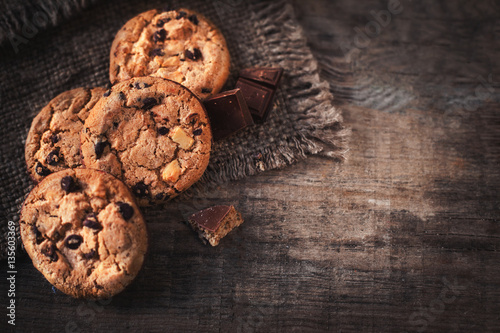 Chocolate chip cookies on dark old wooden table with place for t