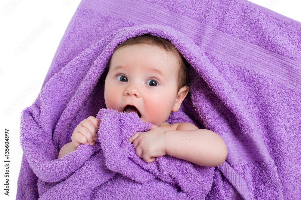 Newborn baby lying down and smiling in a purple towel Newborn baby lying down and smiling in a purple towel