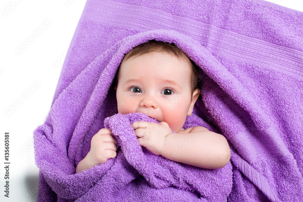 Newborn baby lying down and smiling in a purple towel Newborn baby lying down and smiling in a purple towel