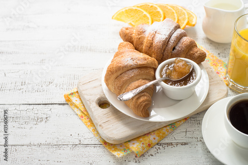 Croissant jam coffee orange jice at white wooden table.  photo