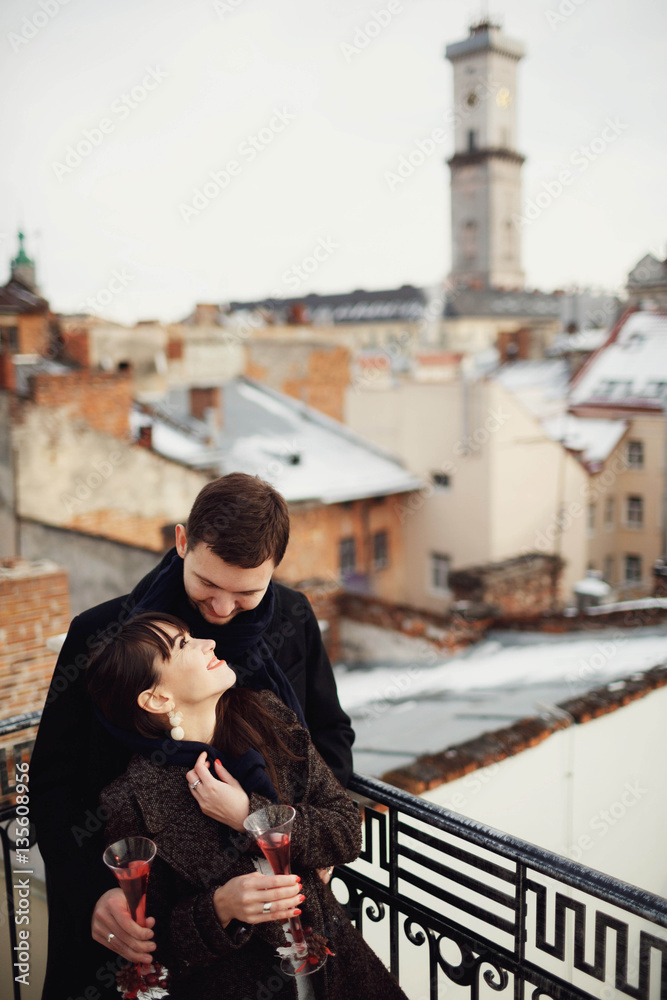beautiful and young couple holds champagne in hands on terrace beautiful and young couple holds champagne in hands on terrace