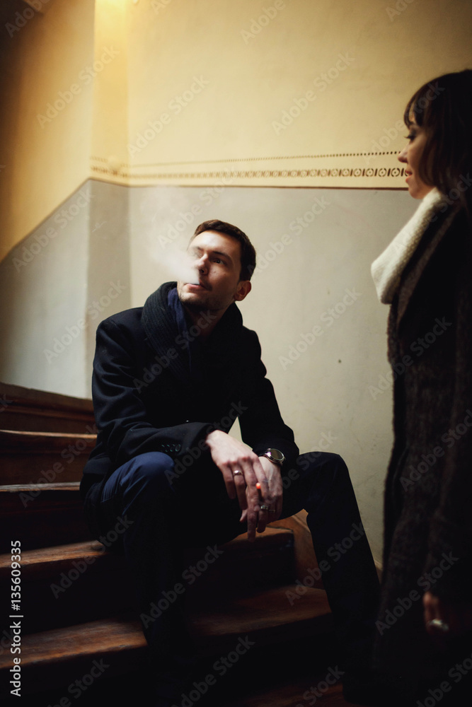 woman stands near man who sits on the stairs woman stands near man who sits on the stairs