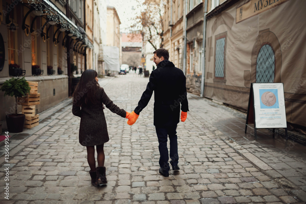 man and woman holding hands in mittens outdoors