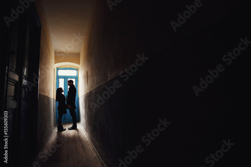 young man and woman standing in a dark corridor