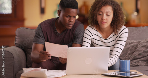 African American couple pays their bills on their laptop photo