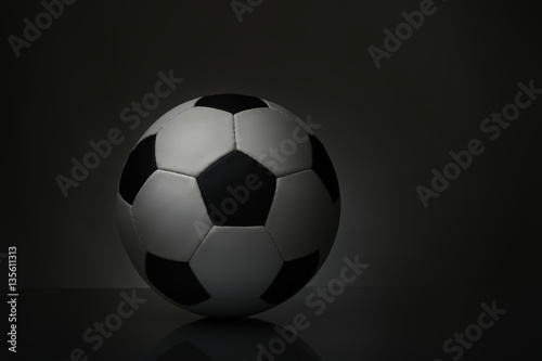 soccer ball with reflection on the table on a dark background © giryakson