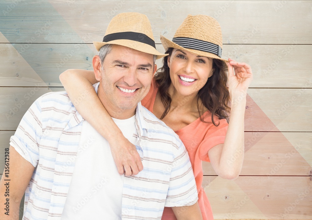 Composite image of couple with hats against wood background Composite image of couple with hats against wood background