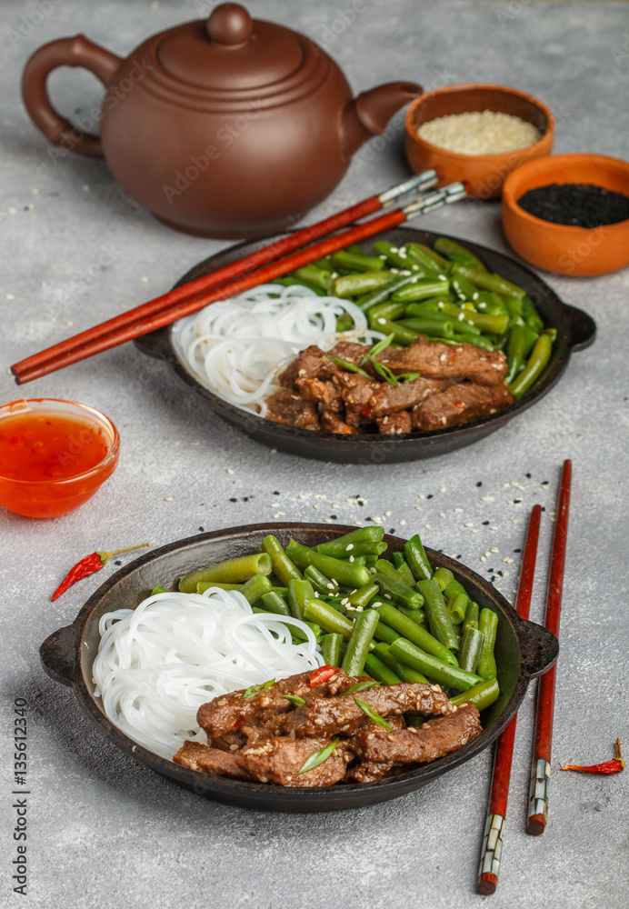 Fried spicy beef with sesame seeds, green beans and rice noodles