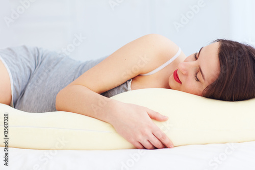 beautiful pregnant woman sleeps comfortable with tummy supporting pillow