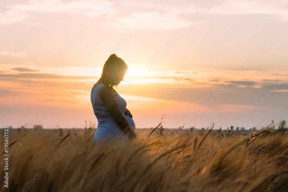 9 months pregnant woman holding belly outdoor sunset. Pregnancy concept.