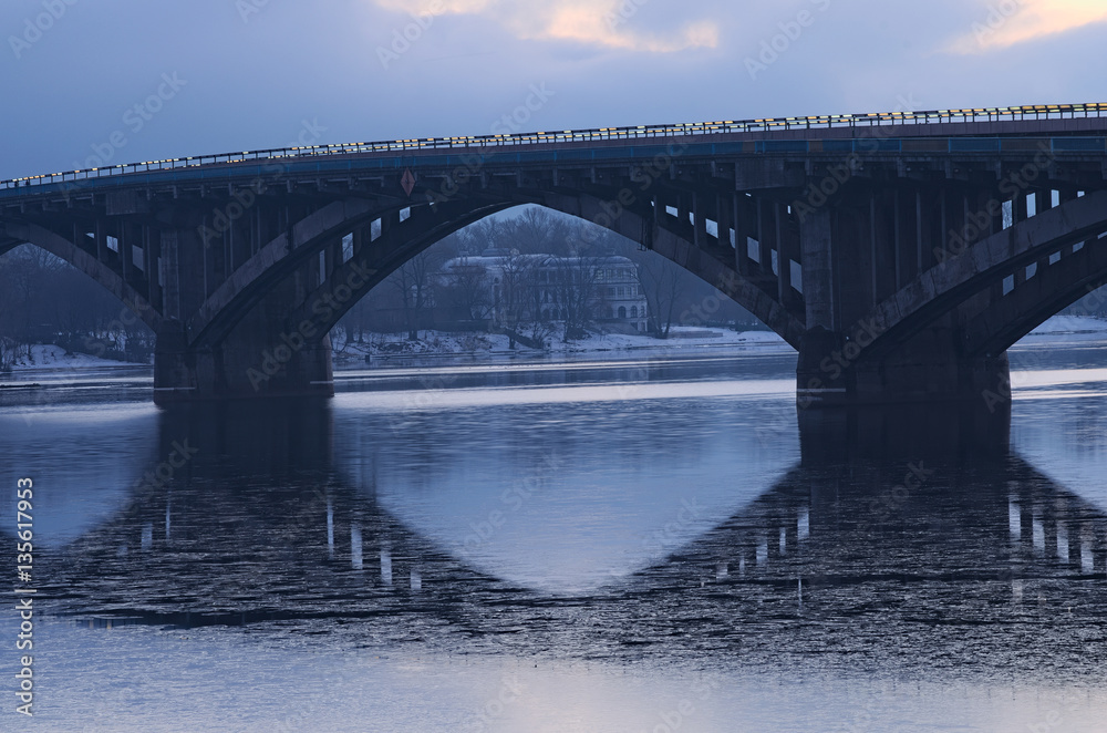 Obraz premium Frosty early morning. Metro bridge reflected in the water. On the other side you can see the white building. Kyiv. Ukraine