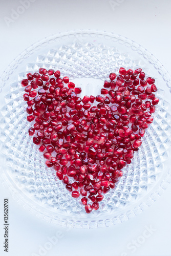 Closeup fresh ripe pomegranate berries in a heart shape