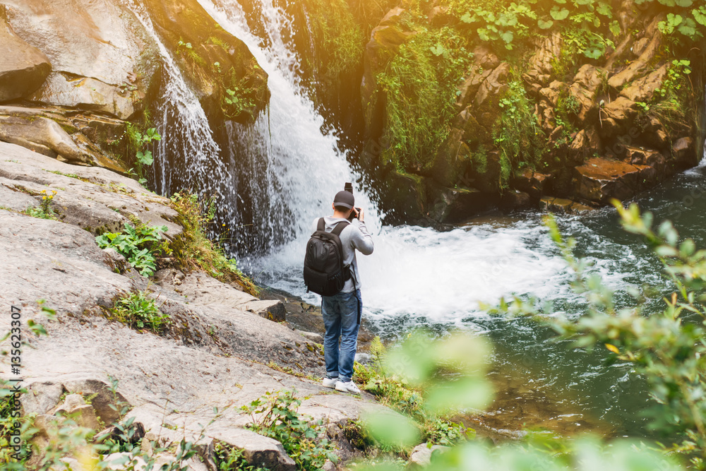 Photographer tourist make photo of waterfall in the Carpathians, Europe, Ukraine