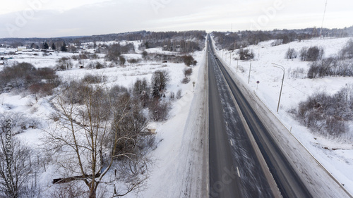 Empty snowy slippery federal three line highway passing through the Russian village. Top view