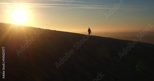 4k cinematic aerial drone shot, woman walking at beautiful sunrise, Dune du Pilat, Arcachon, France photo