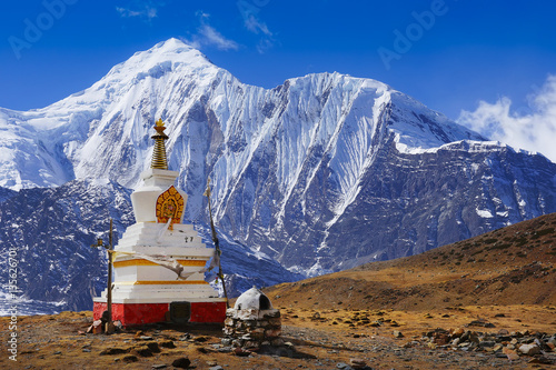 Buddhist stupa at Annapurna Circuit Trek with white summit view, Himalaya mountains, Nepal, Asia. For horizontal postcard or calendar.