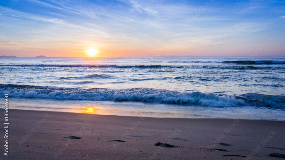 Pegadas na praia ao nascer do sol