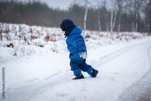 Happy little boy playing outdoor in winter snow