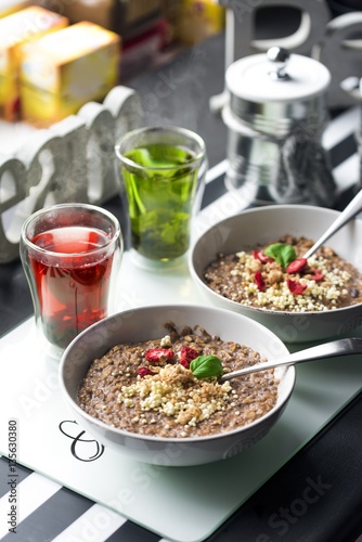 Chocolatiers breakfast for two person with oatmeal, puffed rice, cereals , dried strawberries and  tea prepared in a white bowl. Big inscription Dream above.