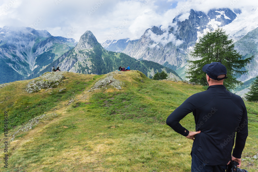 Man dressed in hiking clothing looks out over the snow covered mountains and deep forest valleys during a hike near Courmayeur, Italy Man dressed in hiking clothing looks out over the snow covered mountains and deep forest valleys during a hike near Courmayeur, Italy