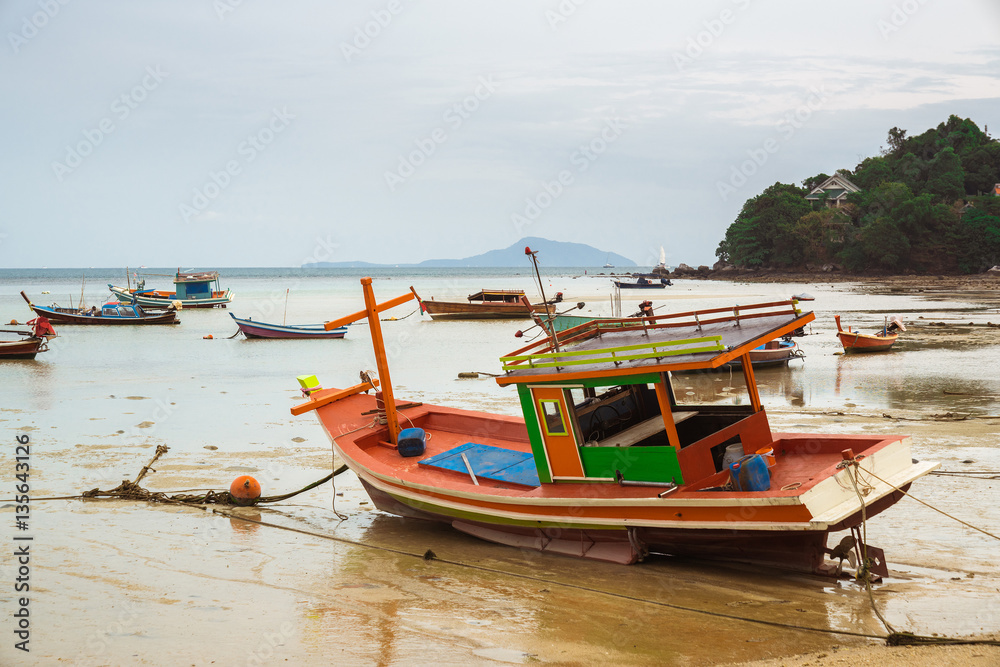 THAILAND, PHUKET, ASIA - FEBRUARY 1, 2017: Thai old fishing small boat at low tide in the shallows. THAILAND, PHUKET, ASIA - FEBRUARY 1, 2017: Thai old fishing small boat at low tide in the shallows.