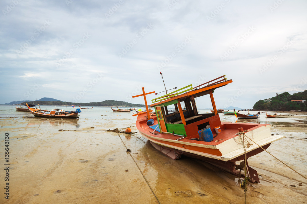 THAILAND, PHUKET, ASIA - FEBRUARY 1, 2017: Thai old fishing small boat at low tide in the shallows.