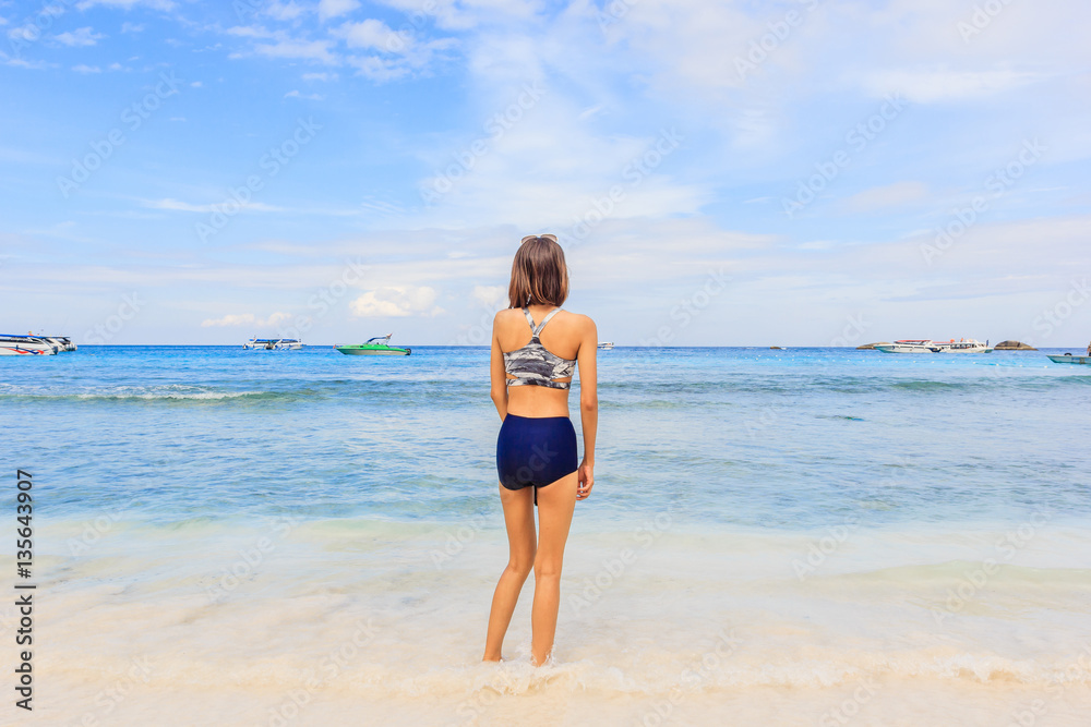 Asian woman in swimsuit standing poses on beach with happy and beautiful blue sky above the sea, Similan Island, Similan National Park, Phang Nga, Thailand